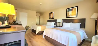 a hotel room with two beds and a desk at Quality Inn & Suites Anaheim at the Park in Anaheim
