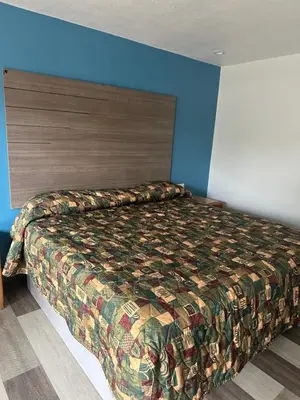 a bed in a bedroom with a blue wall at Palm Inn Hotel near Tyler Mall Riverside in Riverside