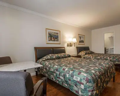 a hotel room with two beds and a table at Palm Inn Hotel near Tyler Mall Riverside in Riverside