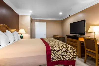 a hotel room with a bed and a flat screen tv at Rodeway Inn Cypress - Buena Park in Cypress