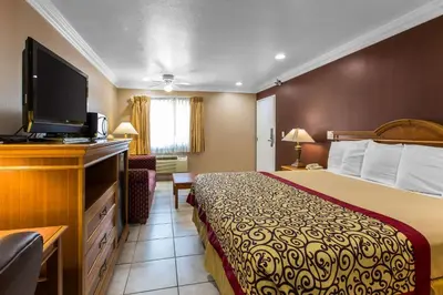 a hotel room with a bed and a flat screen tv at Rodeway Inn Cypress - Buena Park in Cypress