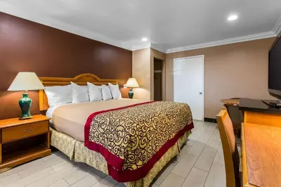a hotel room with a bed and a flat screen tv at Rodeway Inn Cypress - Buena Park in Cypress