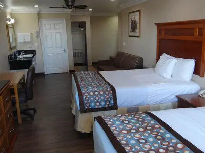 a hotel room with two beds and a desk at Rodeway Inn Cypress - Buena Park in Cypress