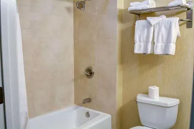 a bathroom with a toilet and a shower with towels at Tilt Hotel Universal-Hollywood, an AGA Collection Hotel in Los Angeles
