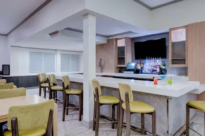 a kitchen with a bar with yellow chairs at Hilton Garden Inn Anaheim/Garden Grove in Anaheim