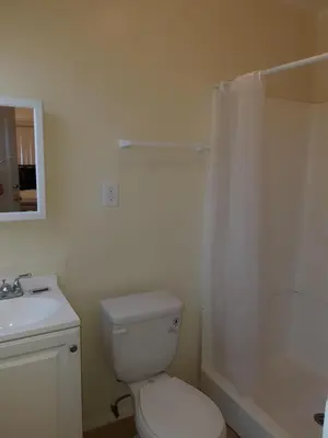 a white bathroom with a toilet and a shower at Pads on Pasadena Ave in Los Angeles