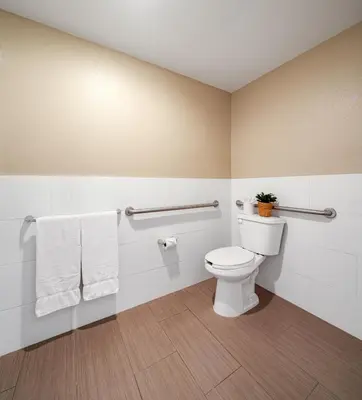 a bathroom with a toilet with towels and a plant at Ayres Hotel Corona - Riverside in Corona