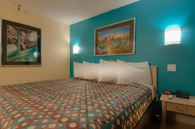 a bedroom with a bed and a blue wall at Vagabond Inn Bakersfield South in Bakersfield
