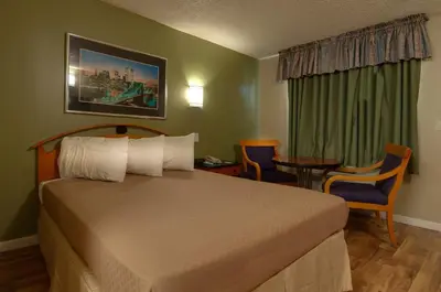 a hotel room with a bed and a table and chairs at Vagabond Inn Bakersfield South in Bakersfield