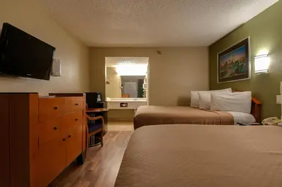 a hotel room with two beds and a flat screen tv at Vagabond Inn Bakersfield South in Bakersfield
