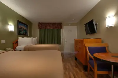 a small hotel room with two beds and a table at Vagabond Inn Bakersfield North in Bakersfield