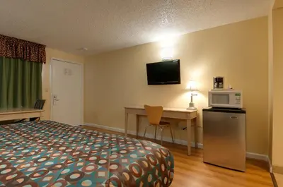 a hotel room with a bed and a desk with a microwave at Vagabond Inn Bakersfield North in Bakersfield