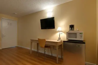 a room with a desk with a microwave and a refrigerator at Vagabond Inn Bakersfield North in Bakersfield