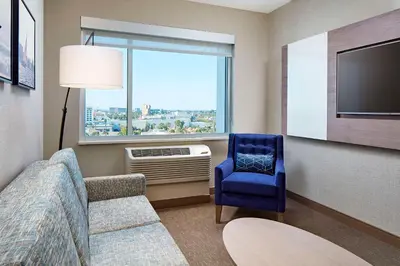 a living room with a couch and a chair and a window at Anaheim Resort Suites in Anaheim