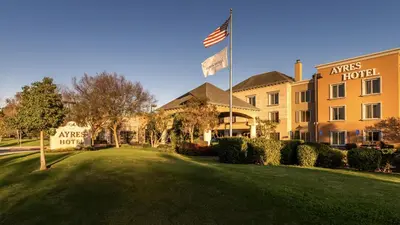 a hotel with an american flag in front of a building at Ayres Hotel Seal Beach - Cypress in Seal Beach