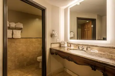 a bathroom with a sink and a mirror and a toilet at Ayres Hotel Seal Beach - Cypress in Seal Beach