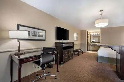 a hotel room with a desk and a bed and a bedroom at Best Western Corona Hotel & Suites in Corona