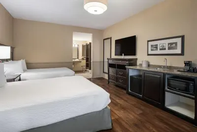 a hotel room with two beds and a flat screen tv at Best Western Corona Hotel & Suites in Corona