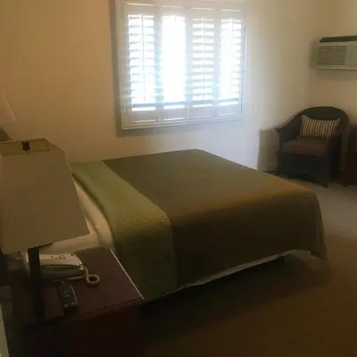 a bedroom with a bed and a window and a chair at Bella Capri Inn and Suites in Camarillo