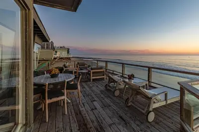 a balcony with tables and chairs and the ocean at Malibu Beach Home Private Sandy Beach and Surf in Malibu