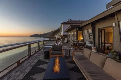 a balcony with a view of the ocean at sunset at Malibu Beach Home Private Sandy Beach and Surf in Malibu