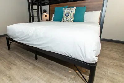 a large bed with white sheets and blue pillows at Magnolia Tree Hotel-Maingate/Anaheim Convention Center in Anaheim