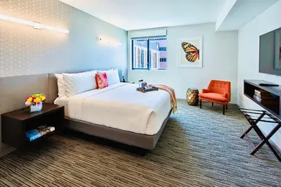 a hotel room with a large bed and a chair at Hotel Mariposa in Los Angeles