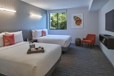a hotel room with two beds and a chair at Hotel Mariposa in Los Angeles