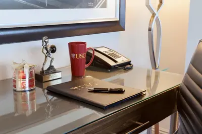 a desk with a book and a pen and a phone at USC Hotel in Los Angeles