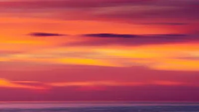 an orange sunset over the ocean with clouds at All 8 Motel in Azusa