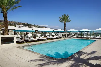 a pool with chairs and umbrellas on a resort at The London West Hollywood at Beverly Hills in Los Angeles