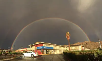a rainbow over a building with a car in a parking lot at Hilltop Inn & Suites in Victorville
