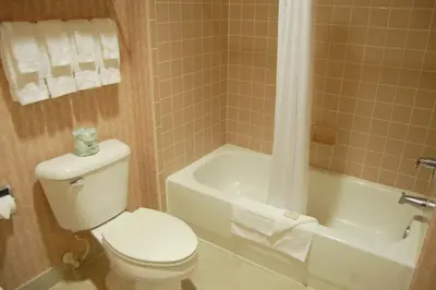 a bathroom with a toilet and a tub and a sink at Landmark Inn Fort Irwin in Fort Irwin