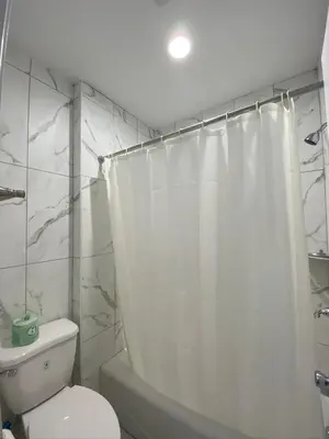 a bathroom with a white shower curtain and a toilet at Redondo Beach Motel - LAX in Gardena