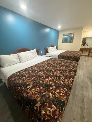 a hotel room with two beds and a blue wall at Anaheim National Inn in Anaheim