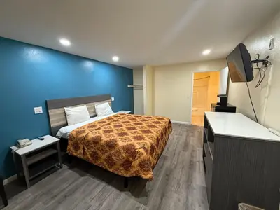 a bedroom with a bed and a blue wall at Anaheim National Inn in Anaheim