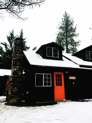 a black house with a red door in the snow at Noon Lodge in Big Bear Lake
