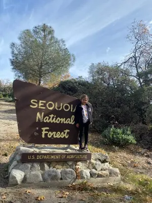 a man standing next to a sign for a national forest at Sequoia National Forest CabinK in Panorama Heights