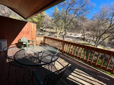 a patio with a table and chairs on a deck at Whispering Pines Lodge in Kernville