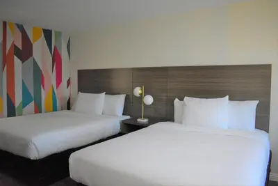 two beds in a hotel room with white sheets at Signature Anaheim Maingate in Anaheim
