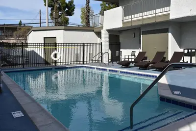 a swimming pool with chairs and a building at Signature Anaheim Maingate in Anaheim