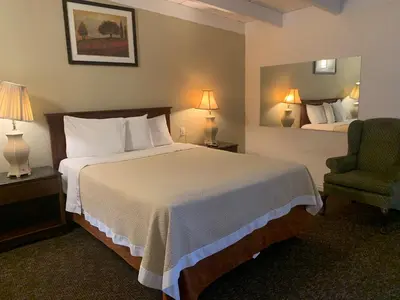 a hotel room with a bed and a chair at Ventura Beach House Motel in Ventura
