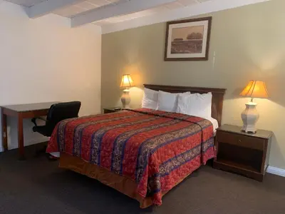 a hotel room with a bed and a desk and lamp at Ventura Beach House Motel in Ventura