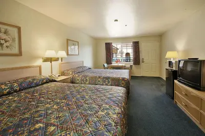 a hotel room with two beds and a flat screen tv at Days Inn by Wyndham Riverside Tyler Mall in Riverside