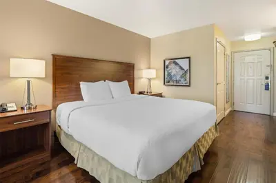 a large bed in a hotel room with two lamps at Best Western Plus John Jay Inn & Suites in Palmdale