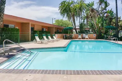 a large swimming pool with chairs and a building at Saga Motor Hotel Pasadena in Pasadena