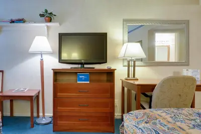a hotel room with a tv on a dresser with two lamps at Saga Motor Hotel Pasadena in Pasadena