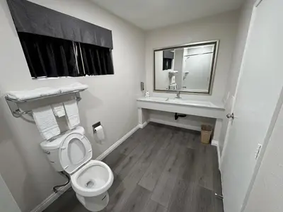 a bathroom with a toilet and a sink and a mirror at Five Star Inn in West Covina