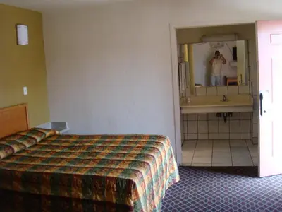 a hotel room with a bed and a person in the mirror at American Inn in South El Monte
