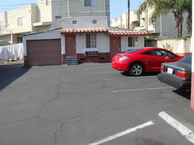 a red car parked in a parking lot in front of a house at American Inn in South El Monte